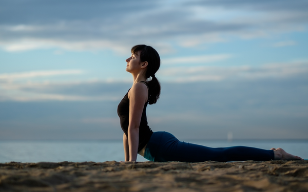 Person doing yoga on the beach - Obus Professional